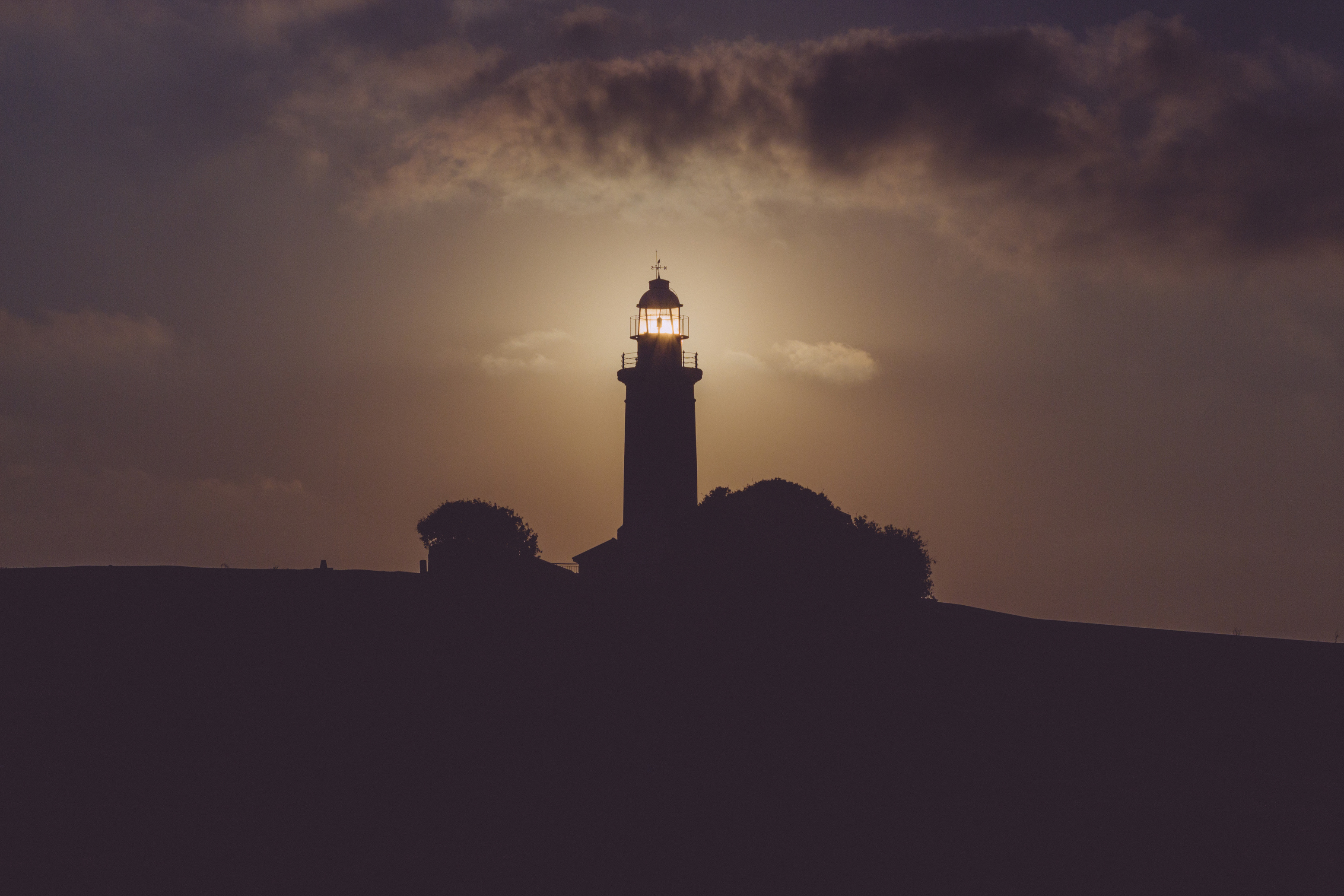 Silhouette of Light House Under Gray Dark Sky